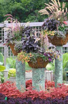 three tall vases with plants in them sitting on top of each other