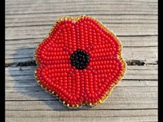 a red flower brooch sitting on top of a wooden table