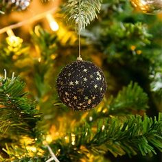 an ornament hanging from the top of a christmas tree with gold stars on it