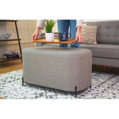 a person holding a tray on top of a footstool in a living room