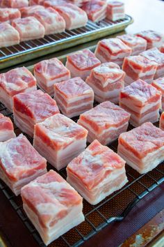 several trays of raw meat sitting on top of a metal rack next to each other