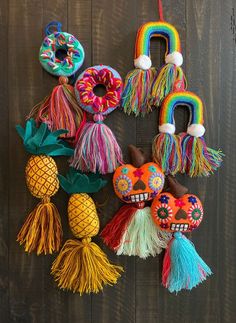 several colorful decorations are hanging on a wooden wall with pineapples and donuts