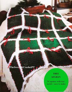 a crocheted christmas afghan on a bed with red and green trimmings