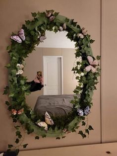 a person taking a selfie in front of a mirror with flowers and leaves on it