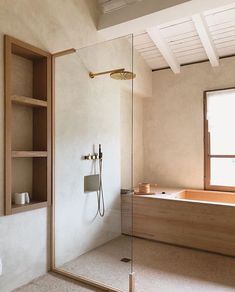 a bathroom with a glass shower door and wooden shelves on the wall next to it