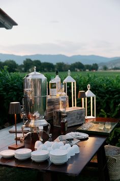 an outdoor table with plates and cups on it