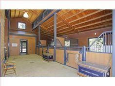 the inside of a horse barn with wooden walls and doors, windows, and railings