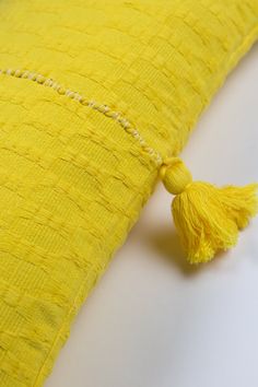 a yellow pillow with tassels on it