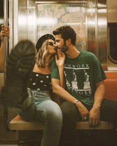 a man and woman sitting on a subway car kissing each other's foreheads