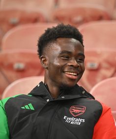 a young man is smiling in front of an empty bleachers seat at a sporting event