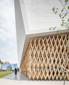 a building made out of wooden slats on the side of a road with a person walking by it