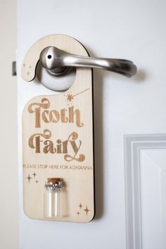 a tooth fairy sign hanging on the wall next to a door handle with two bottles in it