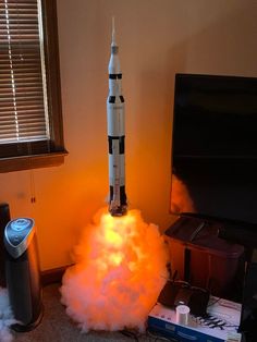 a rocket that is sitting on top of some kind of stand next to a tv