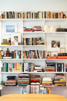 a bookshelf filled with lots of books next to a dining room table and chairs