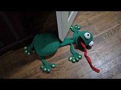 a crocheted frog toy with a toothbrush in it's mouth on the floor