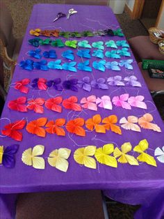 a purple table topped with lots of different colored paper butterflies