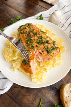 a white plate topped with salmon and mashed potatoes next to a knife and fork