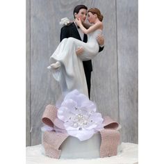 a wedding cake with a bride and groom figurine on top that is holding each other