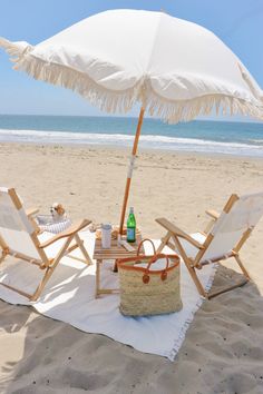 two beach chairs and an umbrella on the sand at the beach with drinks in it