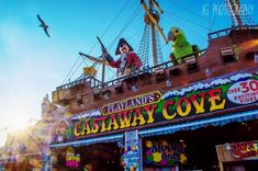 an amusement park with people on the top of it and pirate ship in the background