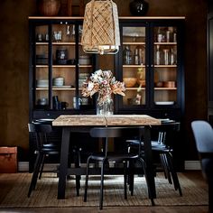 a dining room table with chairs and a vase filled with flowers sitting on top of it