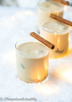 two glasses filled with white liquid and cinnamon sticks on top of snow covered ground, text vegan flatten cremes that girl cooks healthy