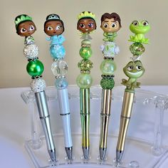 there are five different pens in the holder on the table, each with princess and frog characters