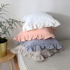 four pillows stacked on top of each other next to a potted plant