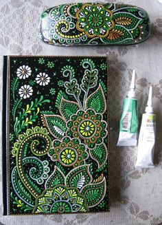 two pens and a notebook on a table next to each other with an intricately designed cover