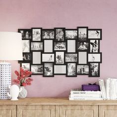 a table with a lamp and some pictures on the wall above it in front of a dresser