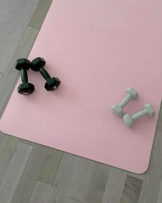 two dumbbells are sitting on a pink mat