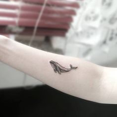 a small whale tattoo on the arm