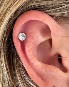 a woman's ear with a single diamond in it