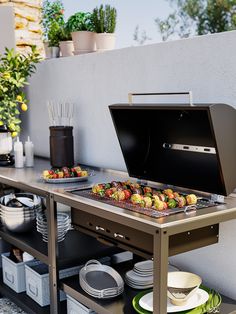 an outdoor bbq grill with plates and bowls on the table next to potted plants