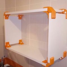 an orange and white shelf in the corner of a bathroom