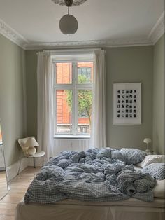 an unmade bed sitting in front of a window