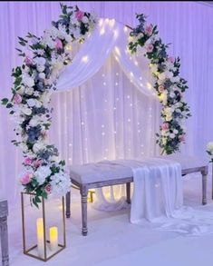 a wedding ceremony setup with white and pink flowers on the altar, candles and drapes