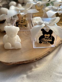 some small white teddy bears sitting on top of a wooden slice with ribbon around them