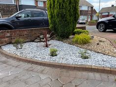 a black truck is parked in front of a brick wall and graveled driveway area