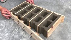 a person is placing cinder blocks into a wooden box on the ground with their hands