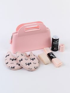 the contents of a pink bag and its contents are laid out on a white surface