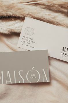 two business cards sitting on top of a bed next to a furnishing material