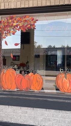 a store front window with pumpkins painted on it's glass and fall decorations in the windows