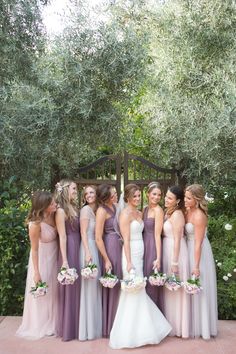 a group of women standing next to each other in front of some trees and bushes