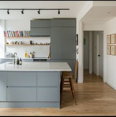 a kitchen with gray cabinets and white counter tops, wooden flooring and hanging bookshelves