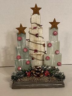 a christmas tree made out of wooden blocks with ornaments around it and stars on top