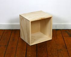 a wooden box sitting on top of a hard wood floor next to a white wall