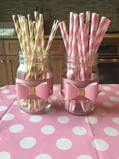 two mason jars with pink and gold striped paper straws in them on a polka dot table cloth