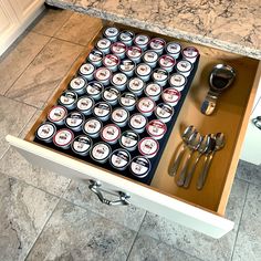 an open drawer in the middle of a kitchen filled with beer cans and utensils