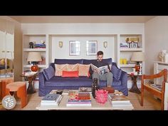 a man sitting on top of a blue couch in a living room filled with furniture